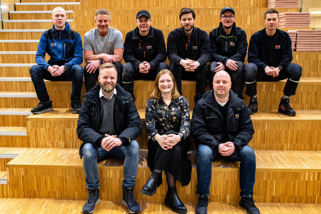 Bildet viser ni personer som sitter i en trapp i Folkeforum i Bodø rådhus. 