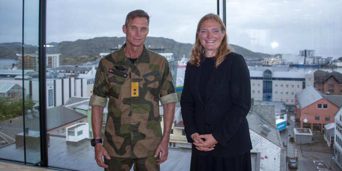Bildet viser Sjef Luftforsvaret Rolf Folland og ordfører Ida Pinnerød. Bildet er tatt foran ett vindu i 6. etasje på rådhuset og i bakgrunnen vises deler av Bodø sentrum, Burøya og Bodø havn. 