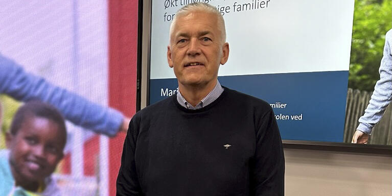 Bildet viser Kjell Hugvik foran en skjerm som viser deler av forsiden til rapporten. 