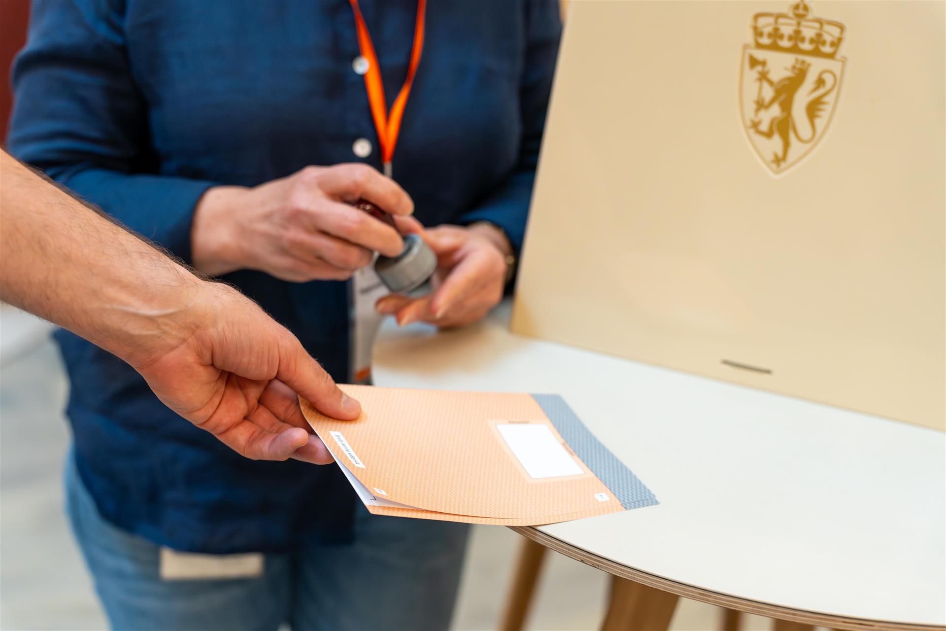 En stemmeseddel gjøres klar for stempel ved valgurnen.