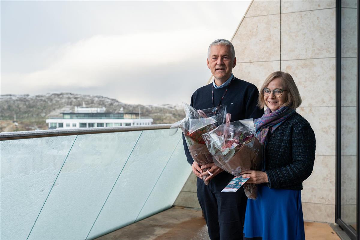 To personer som står ute på en balkong og holder hver sin blomsterbukett.  - Klikk for stort bilde