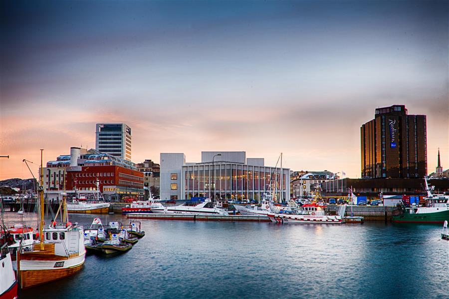 Stormen bibliotek fra kaikanten, med hav foran og nydelig himmel over