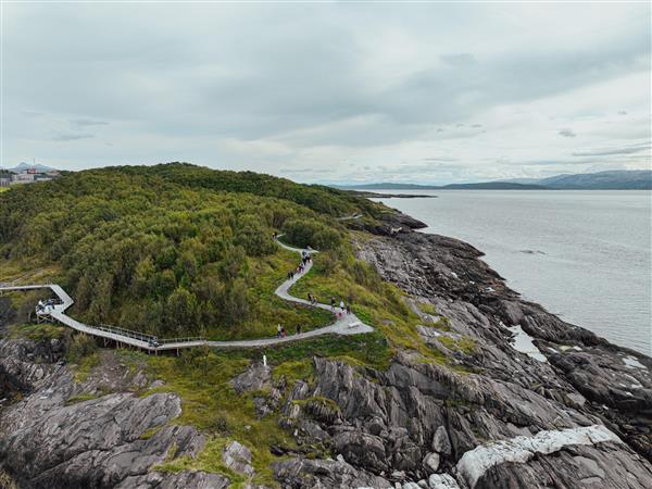En odde langs kyststien i Bodø hvor stien bukter seg over berget og gjennom grøntområder. Havet til høyre.